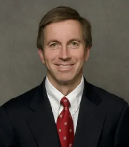 Orthopedist Dr. Michael Maday smiling in a black suit and red tie