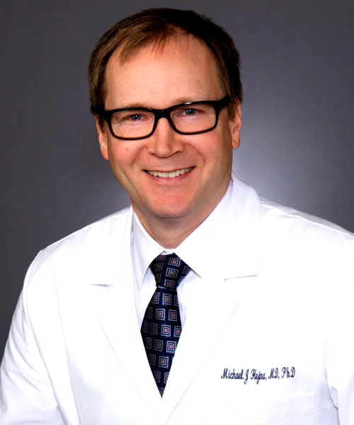 Orthopedist Dr. Michael J. Hejna smiling in his white coat and blue square patterned tie