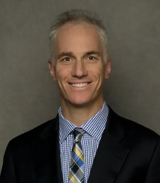 Orthopedist Dr. William Heller smiling in a black suit and blue and yellow patterned tie