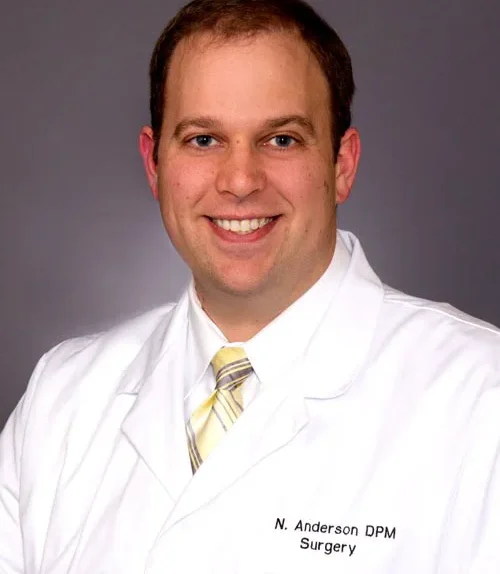 Orthopedist Dr. Nicholas Anderson smiling in his white coat and gold striped tie